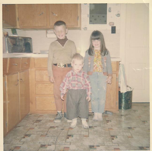 Lori and her brothers as children on the farm posing in the modest kitchen